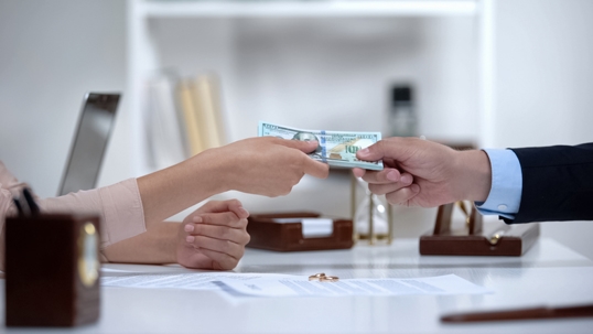 man giving woman money in lawyer's office